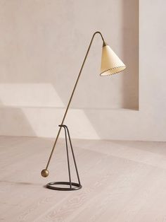 a floor lamp with a white shade on the top and a black stand underneath it