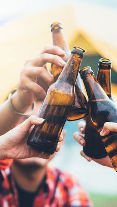 several people are holding beer bottles in their hands