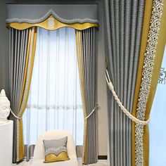 a white chair sitting next to a window covered in drapes and gold trimmings