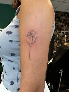 a woman's arm with a single flower tattoo on the left side of her arm