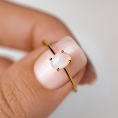 a woman's hand holding an opal ring