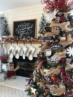 a decorated christmas tree with stockings and stockings hanging from it's sides in front of a fireplace