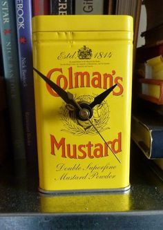 a clock made out of a mustard can sitting on top of a shelf next to books