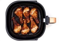 chicken wings cooking in an air fryer on a white background with clippings