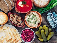 an assortment of food is laid out on a table with bread, vegetables and dips