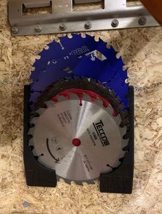 two circular saws are sitting on top of a piece of wood next to a tool holder