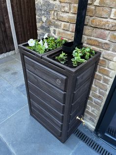 an outdoor planter with plants in it on the ground next to a brick wall