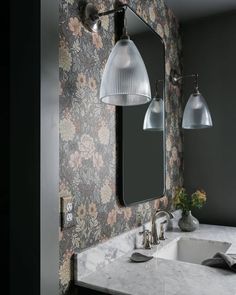 a bathroom sink sitting under a large mirror next to a wall mounted faucet