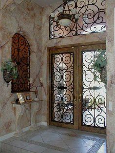 the entrance to a home with wrought iron doors and decorative wallpaper on the walls