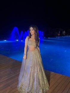 This lehenga set is hand embroidered with all-over sequin, crystal, and cutdana work on a nude gold net base. Paired with a crystal-embellished cold shoulder blouse with tassel detailing and an attached drape.DELIVERY TIMEPlease allow 8-12 weeks for your outfit to arrive.FABRIC DETAILSNetProfessional cleaning only. Anarkali Pre-draped Saree With Sequins For Evening, Hand Embellished Sets For Diwali Party, Glamorous Georgette Gown With Resham Embroidery, Glamorous Gown With Zari Work For Reception, Traditional Drape Sequin Gown For Navratri, Glamorous Traditional Wear With Zari Work For Reception, Glamorous Gown With Resham Embroidery And Traditional Drape, Glamorous Georgette Dress With Zari Work, Hand Embellished Saree Set For Party Wear