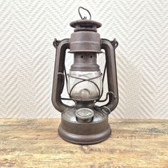 an old fashioned lantern sitting on top of a wooden table