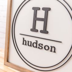 a sign that says hudson on it in black and white letters with a wooden frame