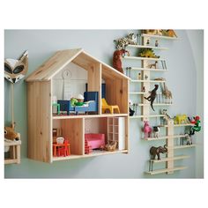 a wooden doll house with shelves and toys on the wall in front of blue walls