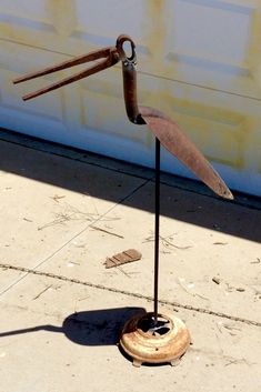 a metal sculpture on the sidewalk with an umbrella shaped like a bird's wing