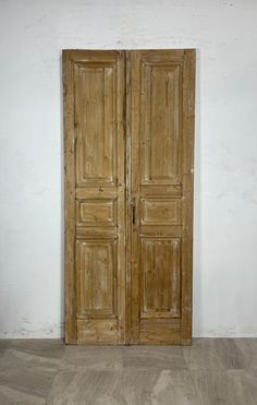 an old pair of wooden doors sitting on top of a hard wood floor next to a white wall