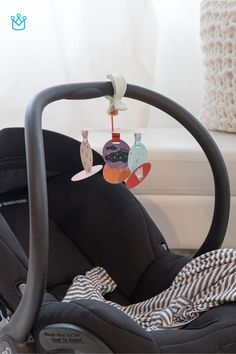 a baby's car seat with an infant mobile hanging from it