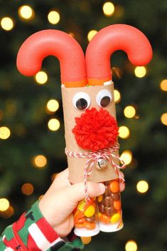 a hand holding up a tube with candy in it and a red nose on top