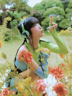 a woman with headphones blowing bubbles while sitting in a field full of wildflowers