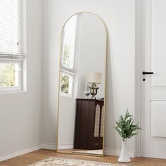 a large mirror sitting on top of a wooden floor next to a vase filled with flowers