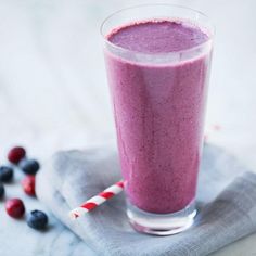 a smoothie with blueberries and raspberries is on a napkin next to some strawberries