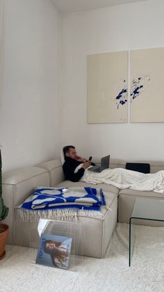 a man sitting on top of a couch in a living room next to a cactus