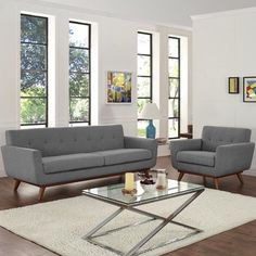 a living room with two gray couches and a white coffee table in front of windows