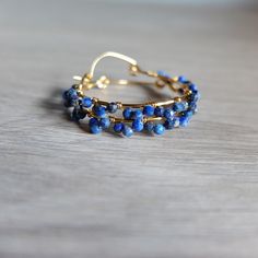 These beautiful fine  hoop earrings have beautiful faceted blue Lapis Lazuli  and gold filled wire .  The gemstones are  deep  blue   color with natural calcite stripes  The genuine  beads are wire wrapped around gold filled  hoops in small clusters The gemstones are faceted genuine lapis lazuli and they are completely handwrapped by me with gold filled wire   Diameter of the hoops is  3,00  cm- total diameter is 3.50 cm The round shaped, faceted stones measure  3 mm approximately    please note Formal Lapis Lazuli Jewelry With Round Beads, Blue Wire Wrapped Hoop Earrings As Gift, Blue Small Hoop Earrings With Wire Wrapping, Blue Wire Wrapped Hoop Earrings For Gift, Blue Wire Wrapped Small Hoop Earrings, Blue 14k Gold Filled Wire Wrapped Jewelry, Blue Small Hoop Wire Wrapped Earrings, Small Blue Wire Wrapped Hoop Earrings, Blue Small Hoop Earrings Wire Wrapped