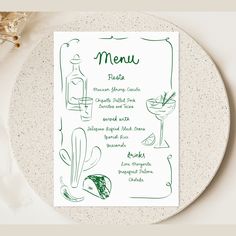 a menu card on a plate next to a drink glass and utensils in a vase