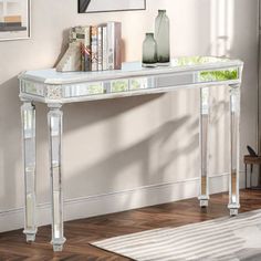 a white console table with books and vases on top