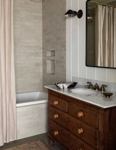 a bathroom with a sink, mirror and bathtub