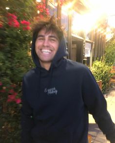 a man in a hoodie is smiling for the camera