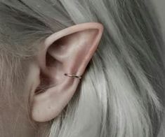 a woman with grey hair wearing an ear piercing