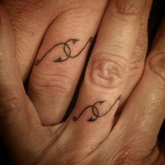 two fingers with tattoos on them, one has an arrow and the other has a heart