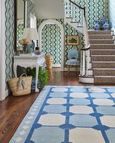 a blue and white rug in the middle of a room with stairs leading up to it