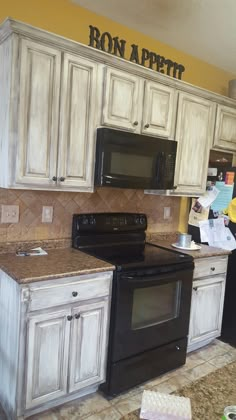 a kitchen with white cabinets and black stove top oven in the middle of the room