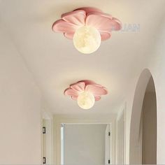 two ceiling lights with pink flowers on them in a hallway between white walls and archways