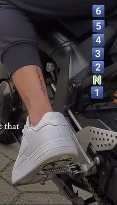 a person riding a motorcycle with their foot on the handlebars and numbers behind them