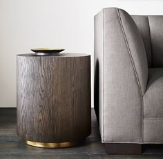 a grey couch sitting next to a wooden table on top of a hard wood floor