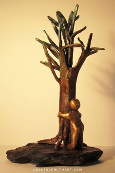 a bronze sculpture of a person hugging a tree