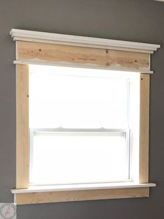 an empty window in the corner of a room with gray walls and white trim on the windowsill