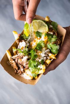 a person cutting into a taco salad with limes and cilantro on the side