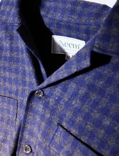 a close up view of a blue shirt with a white label on the collar and chest