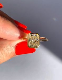 a woman's hand holding an engagement ring with a yellow diamond in the center