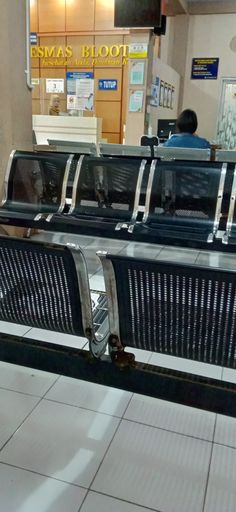 two empty benches sitting in front of an airport check - in counter with luggage on them