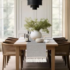 a dining room table set with place settings and flowers in a vase on the table