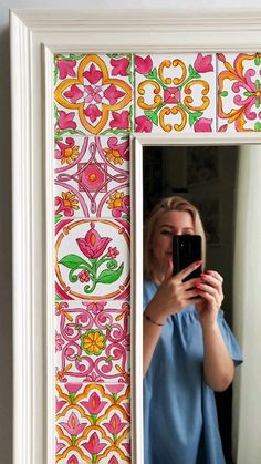 a woman taking a selfie in front of a mirror with flowers painted on it