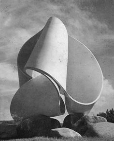 a black and white photo of an abstract sculpture in the middle of rocks with clouds behind it