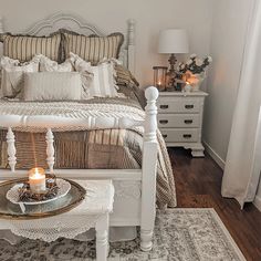 a white bed sitting next to a table with a candle on it