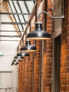 several lights hanging from the side of a building next to a brick wall and ceiling