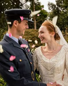 a man and woman in wedding attire standing next to each other with confetti falling from the sky